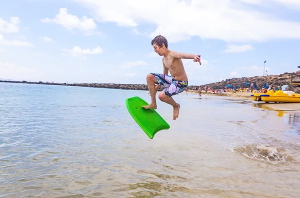 Niño feliz disfruta surfeando en las olas — Foto de Stock