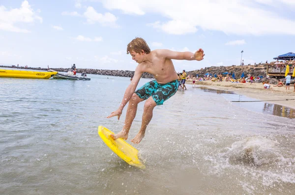 Szczęśliwy chłopiec cieszy się surfingu w fale — Zdjęcie stockowe