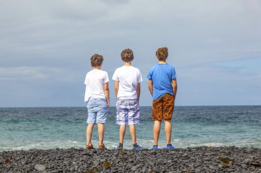 Boys have fun at the black volcanic beach clipart