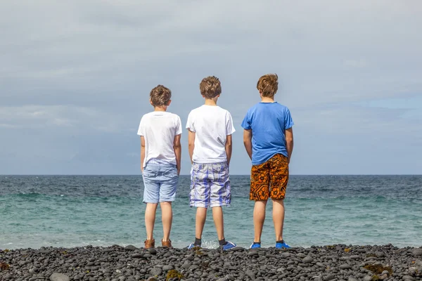 Мальчики веселятся на черном вулканическом пляже — стоковое фото