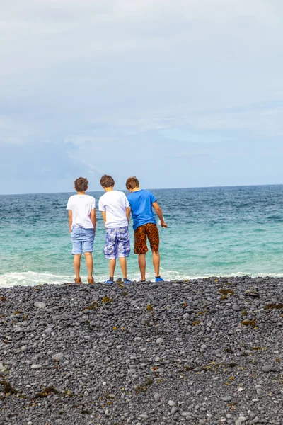 Les garçons s'amusent à la plage volcanique noire — Photo