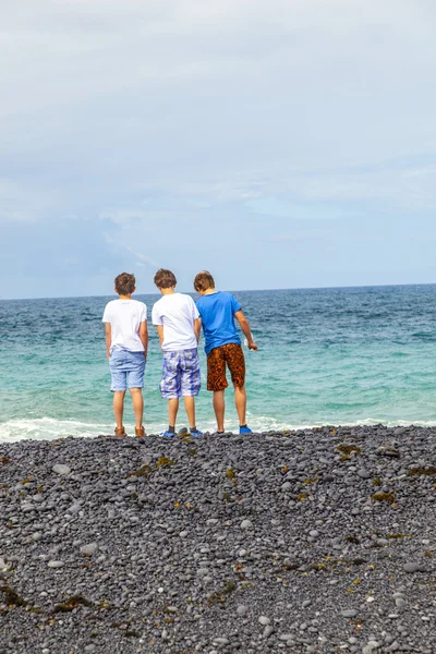 Pojkar har roligt på den svarta vulkaniska stranden — Stockfoto