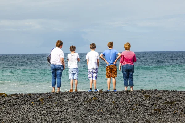 Familie beobachtet die Wellen am schwarzen Vulkanstrand — Stockfoto