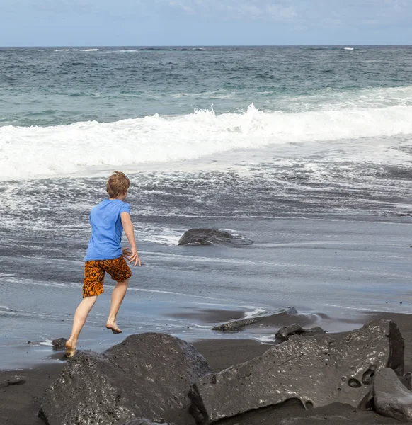 Menino se diverte na praia vulcânica preta — Fotografia de Stock