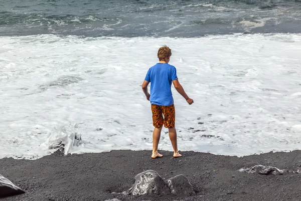 남자는 검은 화산 해변에 재미가 — 스톡 사진