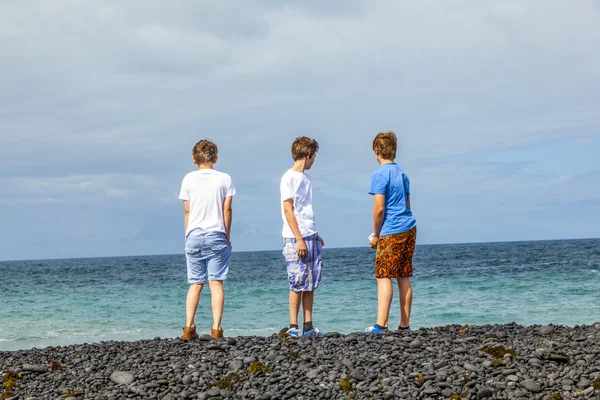 Los chicos se divierten en la playa negra volcánica —  Fotos de Stock