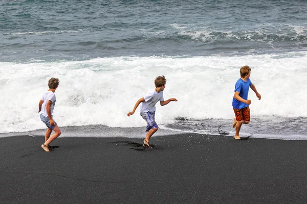 Хлопчики розважаються на чорному вулканічному пляжі — стокове фото