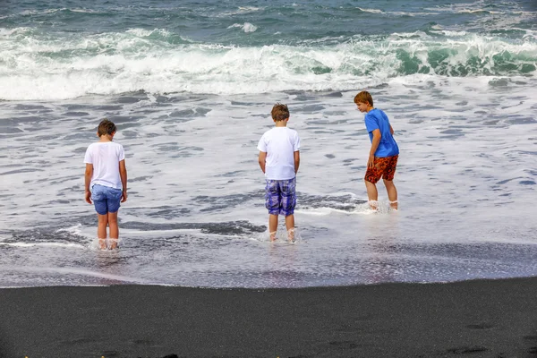 Los chicos se divierten en la playa negra volcánica — Foto de Stock