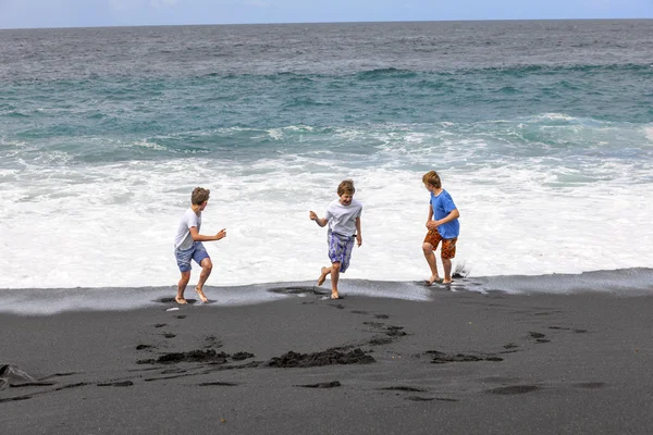 Pojkar har roligt på den svarta vulkaniska stranden — Stockfoto