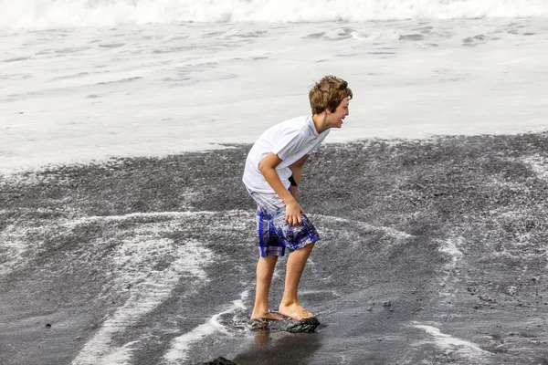 男の子は黒い火山ビーチで楽しい時を過す — ストック写真