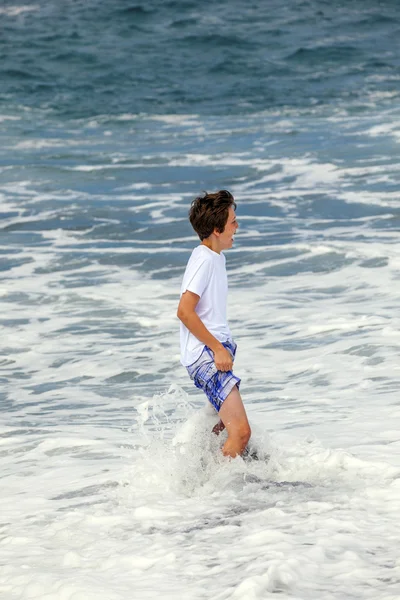 Chlapec má zábavu v vylétli na černé vulkanické pláži — Stock fotografie