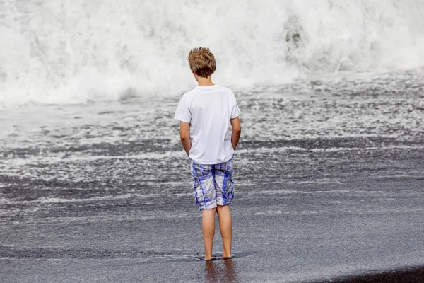 Chlapec má zábavu v vylétli na černé vulkanické pláži — Stock fotografie