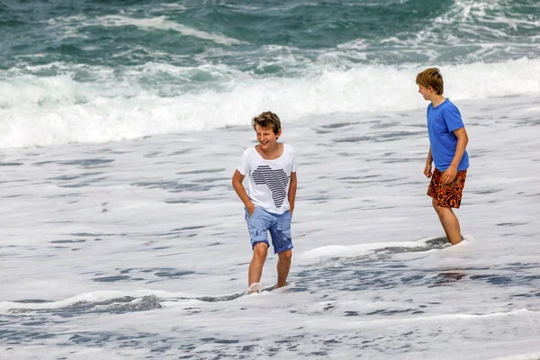 I ragazzi si divertono sulla spiaggia vulcanica nera — Foto Stock