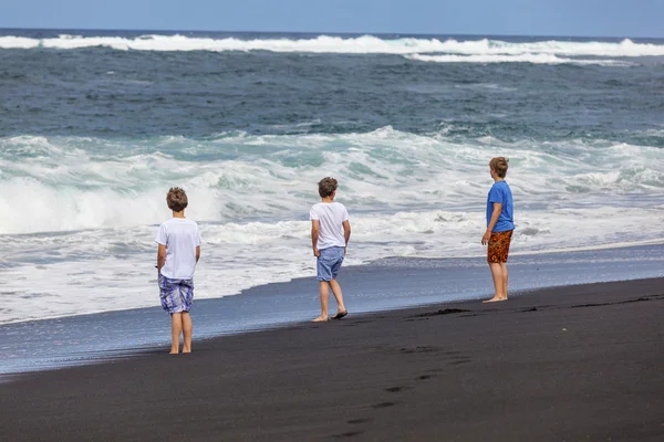 Boys have fun at the black volcanic beach — Stock Photo, Image