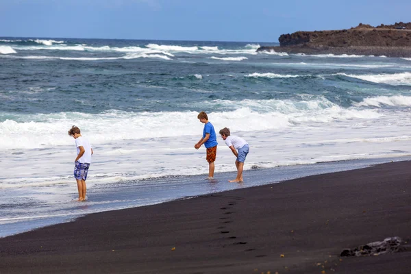 Хлопчики розважаються на чорному вулканічному пляжі — стокове фото