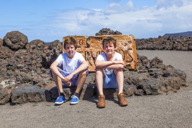 Brothers sitting on a rock and have a rest clipart