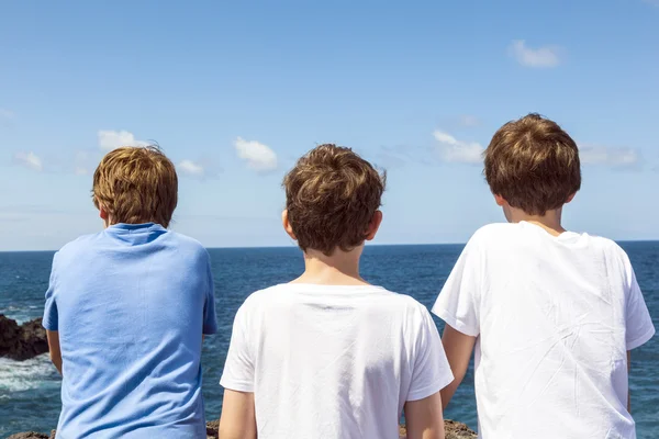 Three friends watching the rocks and waves — Stock Photo, Image