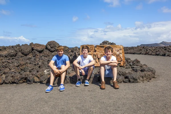 Three friends sitting on a rock and have a rest — Stock Photo, Image