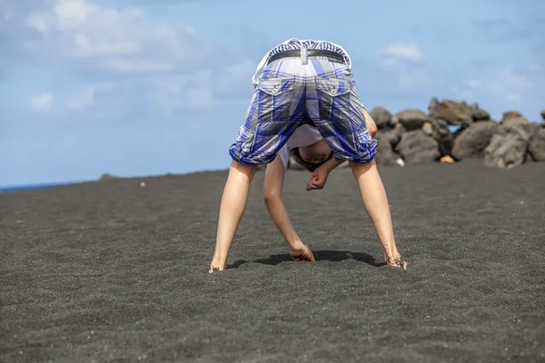 Jongen verzamelt edelstenen op de vulkanische strand — Stockfoto