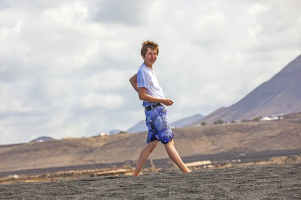 Boy collects gemstones at the volcanic beach — Stock Photo, Image