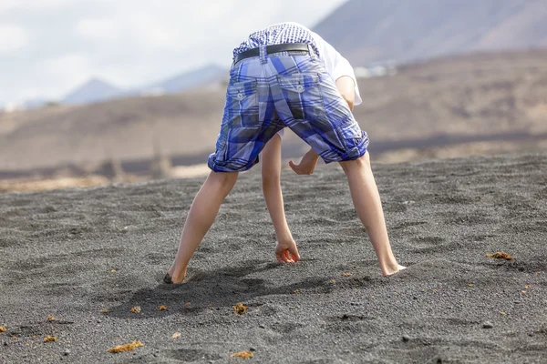 Ragazzo raccoglie pietre preziose presso la spiaggia vulcanica — Foto Stock
