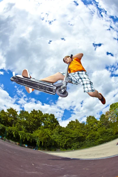 Menino indo para o ar com sua scooter — Fotografia de Stock