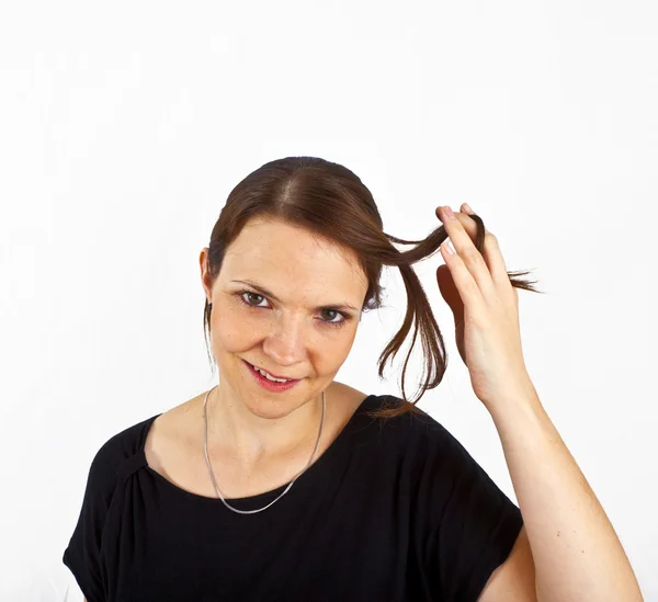 Attractive young woman smiles and plays with her hair — Stock Photo, Image
