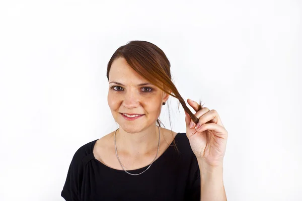 Atractiva joven sonríe y juega con su pelo — Foto de Stock