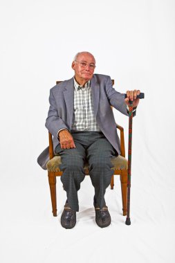 Old friendly man sitting in his armchair with walking stick clipart