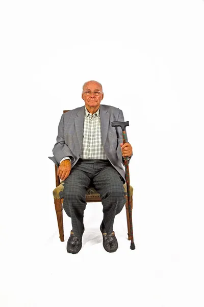 Velho homem amigável sentado em sua poltrona com bengala — Fotografia de Stock