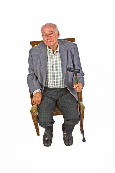 Viejo hombre amistoso sentado en su sillón con bastón —  Fotos de Stock