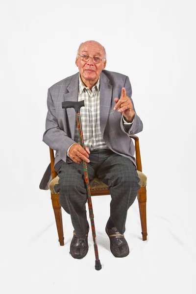 Vieil homme amical assis dans son fauteuil avec bâton de marche — Photo