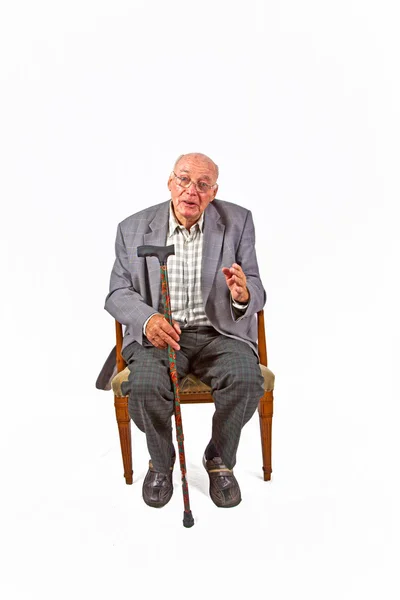 Старий доброзичливий чоловік сидить у кріслі з палицею — стокове фото