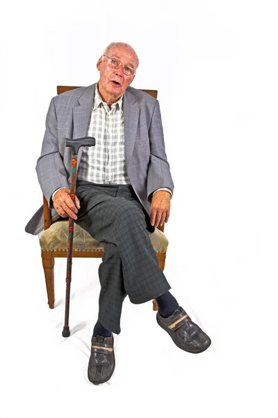 Old friendly man sitting in his armchair with walking stick — Stock Photo, Image
