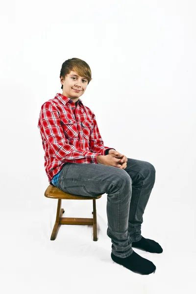 Chico joven de aspecto amistoso con camisa roja sentado en un sc de madera —  Fotos de Stock