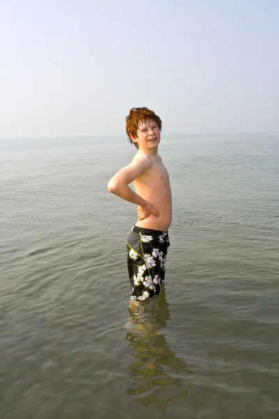 Aranyos fiú ott állt a vízben, a strand, Velence, Olaszország. — Stock Fotó