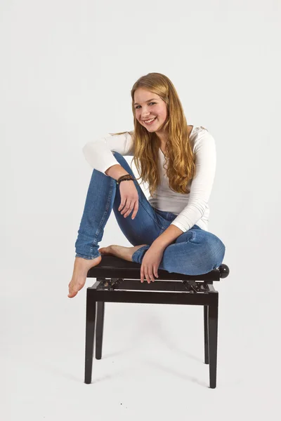 Ganzkörperporträt eines glücklichen schönen Mädchens, das auf einem Klavier sitzt — Stockfoto