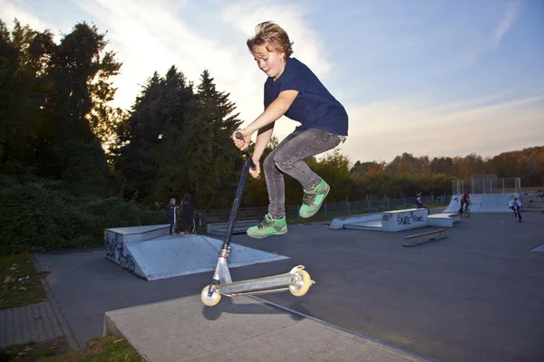 Мальчик прыгает на скутере в скейтпарк — стоковое фото