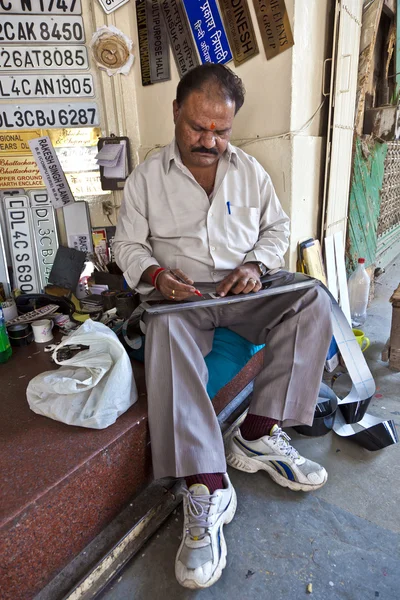 Worker is painting car plates by hand — Stock Photo, Image