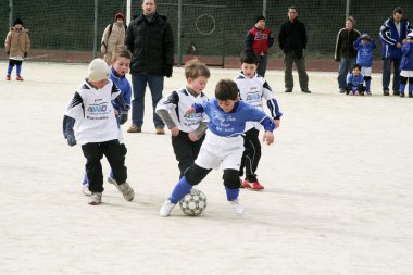 Children playing soccer in winter at an outdoor arena clipart