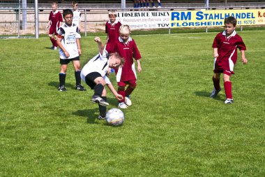 Children playing soccer in summer in an outdoor grass arena clipart