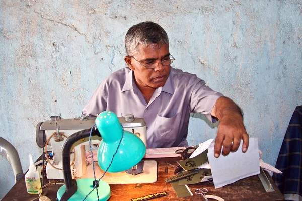 stock image Sewer at the market is sewing name badges for customers