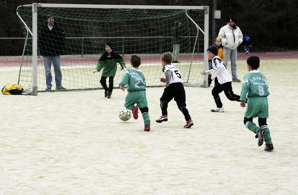Kinder spielen im Winter Fußball in einer Freiluftarena — Stockfoto