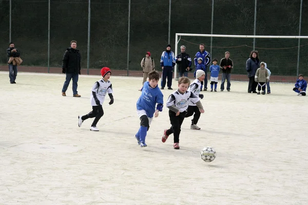 Dzieci gry w piłkę nożną w zimie na zewnątrz arena — Zdjęcie stockowe