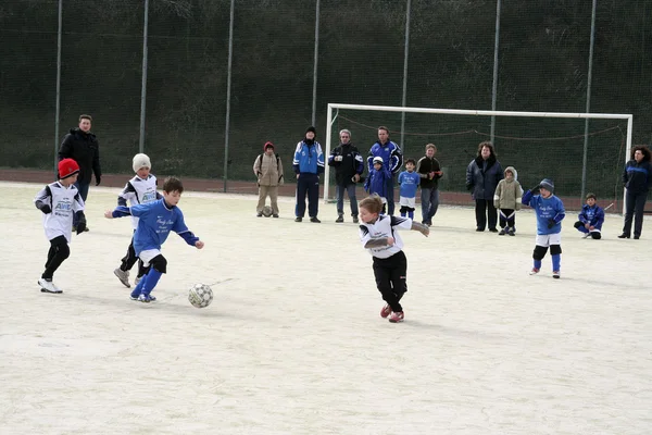 Kinder spielen im Winter Fußball in einer Freiluftarena — Stockfoto