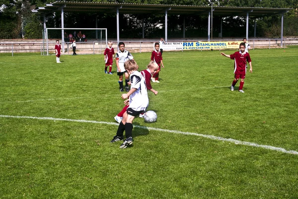 Gyermekek fociznak, nyarán egy szabadtéri füves arénában — Stock Fotó