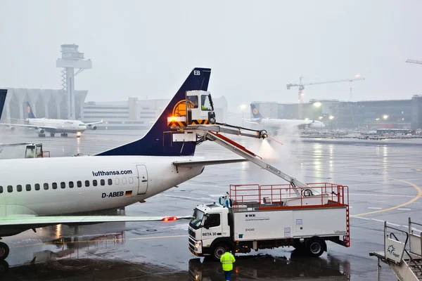 Werknemer deices de vleugel van de vlakte in de luchthaven van frankfurt op de — Stockfoto