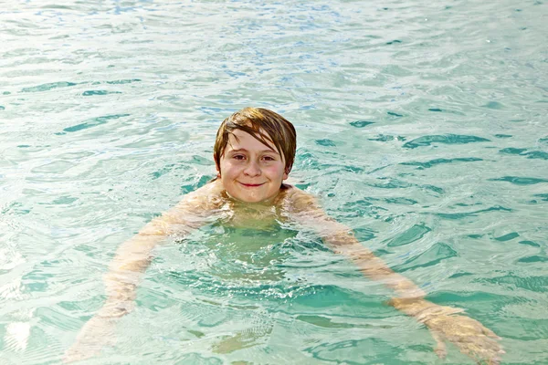 Ευτυχής κομψός αγόρι απολαμβάνει κολύμπι στον ωκεανό σαφές — Φωτογραφία Αρχείου