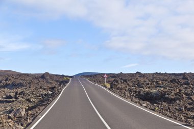 Street through volcanic area in Timanfaya national park clipart