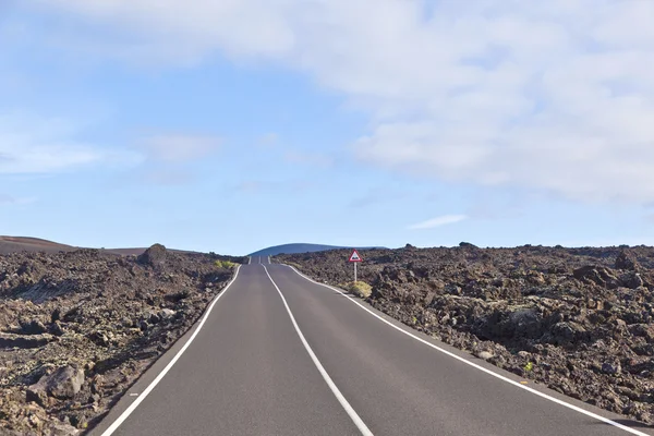 Street through volcanic area in Timanfaya national park — Stock Photo, Image